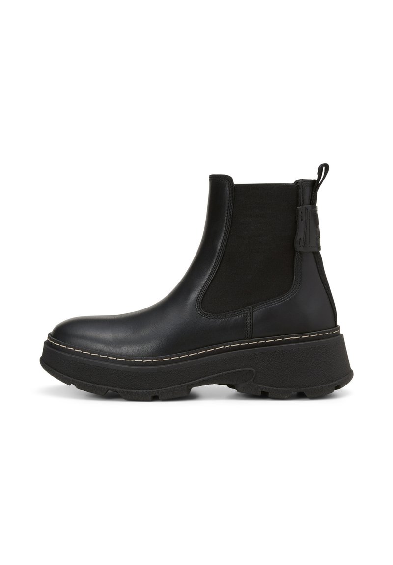 Bottines Chelsea noires avec une semelle épaisse, en cuir lisse, panneaux latéraux élastiques et une languette arrière; détail de couture visible.