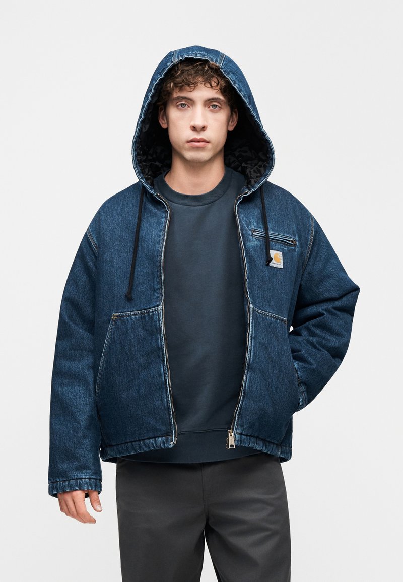 Denimjakke med hætte, to forlommer og lynlås. Mørkeblå farve med en tekstureret inderforing og kontrastsyede sømme.