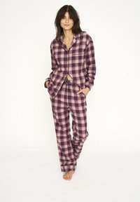 Plaid pajama set in shades of purple and light pink; long-sleeved button-up top with chest pocket and drawstring pants. Soft texture.