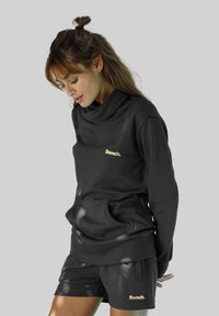 Felpa grigio scuro con colletto a cappuccio e tasca anteriore, con un logo dorato "Bench.". Abbinata a pantaloni corti coordinati, entrambi realizzati in tessuto morbido.