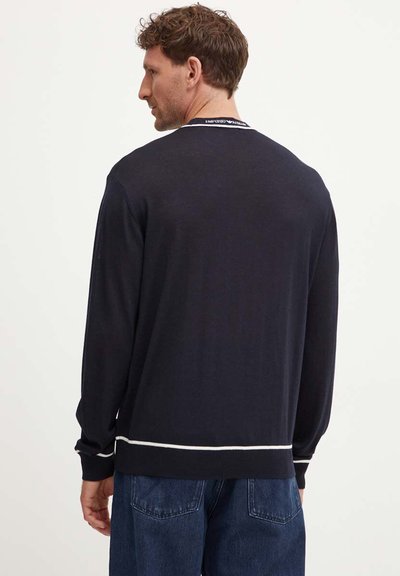 Maglione lavorato a maglia blu navy con maniche lunghe, caratterizzato da una striscia orizzontale bianca sull'orlo e nei dettagli del collo. Texture liscia.