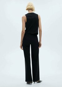 Costum format din două piese, de culoare neagră, care include un top fără mâneci și pantaloni lungi, largi. Material neted, cu un design minimalist și linii curate, drepte.