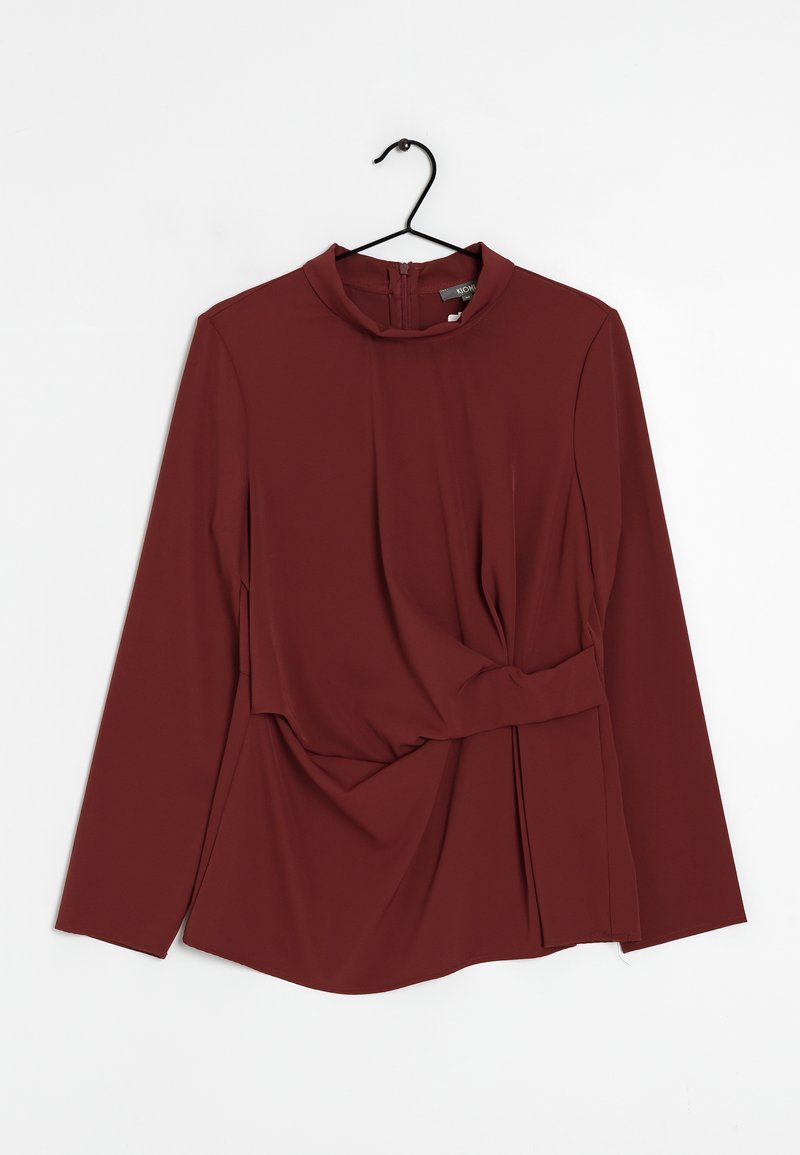 Mörkröd långärmad topp med hög krage, plisserad frontdesign, samlad midjedetalj och subtil lyster. Avslutas med en dragkedja i ryggen.