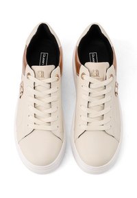 Zapatillas de deporte de cuero beige con suelas de goma blanca, diseño de cordones, detalles en marrón en el talón y logotipos grabados.
