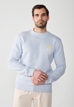 Felpa azzurra chiaro realizzata in morbido cotone, con scollatura rotonda e stampe grafiche di sole e onde. Maniche lunghe e polsini a coste.