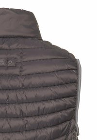 Mørkegrå polstret vest med høj krave, der har quiltede vandrette linjer og en lynlås langs siden. Diskret brandingdetalje.}}