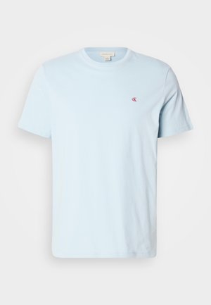 Lyseblå t-skjorte i bomull med korte ermer, rund hals og en liten rød logo på brystet. Glatt tekstur, casual design.