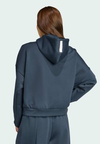 Felpa blu navy con vestibilità rilassata, tessuto testurizzato e un ampio cappuccio. Presenta un'etichetta sul retro e polsini e orlo elasticizzati.