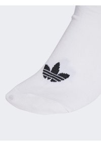 Fehér pamut zokni, fekete Adidas logóval, három levél alakú formával, vízszintes fekete csíkokkal kiemelve, sima textúrával.