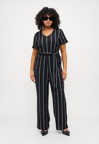 Black striped jumpsuit with short sleeves, a belted waist, and wide legs. Features textured vertical lines in various colors. Accessories include sunglasses.