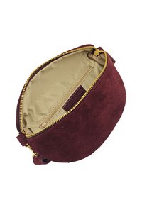 Sac en velours bordeaux de forme ronde avec une fermeture éclair dorée. L'intérieur est équipé d'une doublure en tissu beige et d'une poche zippée supplémentaire pour une meilleure organisation.