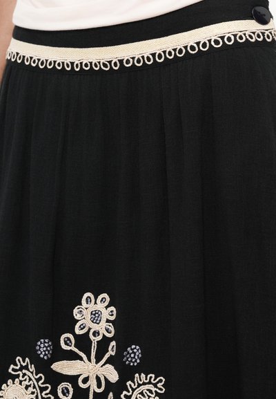 Črna krila z zapletenim cvetnim vezenjem v bež in modri barvi, z teksturirano tkanino in okrasnim pasom.