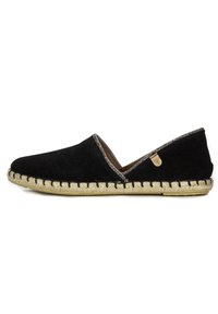 Zapato negro de ante sin cordones con suela de yute trenzado, acentos plateados a lo largo de la abertura y una pequeña etiqueta con el logo en el costado.