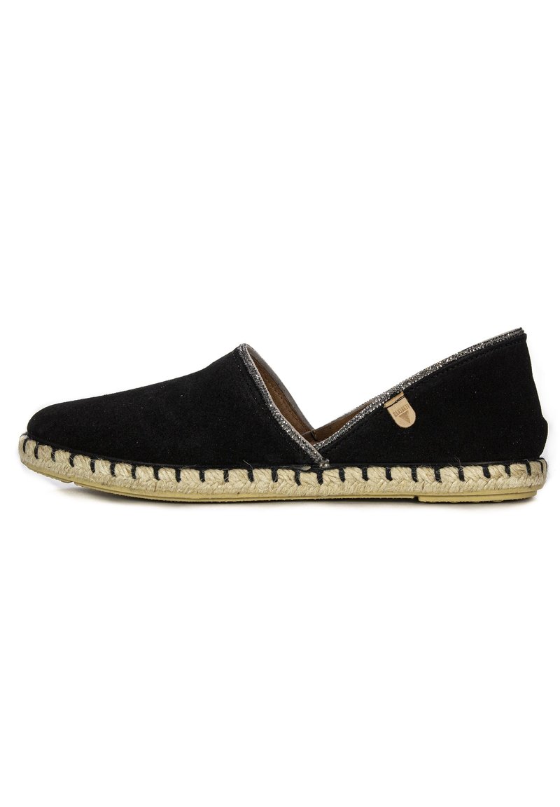 Zapato negro de ante sin cordones con suela de yute trenzado, acentos plateados a lo largo de la abertura y una pequeña etiqueta con el logo en el costado.