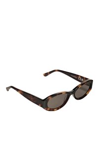 Hnědé želvovinové sluneční brýle s oválnými skly, silnými obroučkami a štíhlými stranami. Skla mají mírné zabarvení pro ochranu před sluncem.