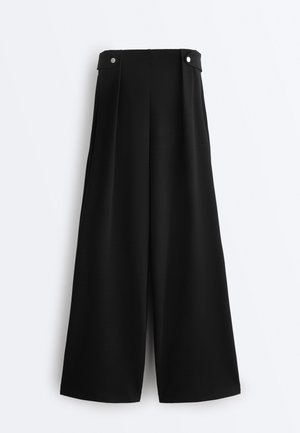 Musta, korkeavyötäröinen, leveälahkeinen housut, joissa on napilliset vyötärönauhakiinnikkeet ja sileä etupuoli, valkoisella taustalla esitetty.