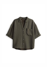 Chemise à manches courtes de couleur vert olive, en tissu texturé côtelé, avec une poche sur le devant et un col boutonné. Elle comporte cinq boutons sur le devant.