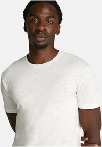 T-shirt bianca a maniche corte realizzata in tessuto testurizzato, con colletto rotondo e logo discreto sul petto.