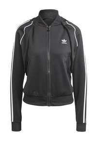 Schwarze Sportjacke aus glattem Stoff mit einem Reißverschluss, geripptem Kragen und weißen Seitestreifen. Adidas-Logo auf der Brust.