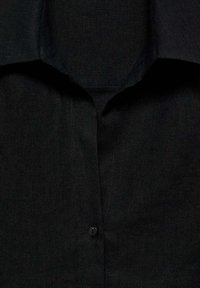 Camicia nera con texture, caratterizzata da colletto a punta, chiusura a bottoni e un tessuto morbido, che mette in mostra un design semplice e moderno.