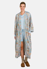 Musterhafter, leichter Kimono in Blautönen mit Paisleymuster. Getragen über einem passenden Kurzarmtop und Shorts, kombiniert mit bequemen Hausschuhen.