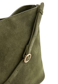Olivengrøn suedetaske med en blød tekstur, der har et rundt hardwareelement i rosaguld og en praktisk justerbar rem.