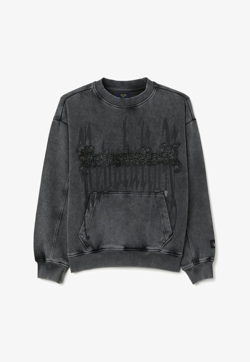 Sudadera gris con cuello redondo, que presenta un bolsillo frontal y un detalle gráfico texturizado en negro en el centro. Tejido suave, ajuste relajado.