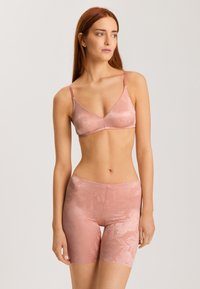 Vaaleanpunainen pitsinen bralette, jossa on säädettävät hihnat, sileä pinta ja kukkakuosi. Yhdistetty saman sävyisiin pitsisiin shortseihin.