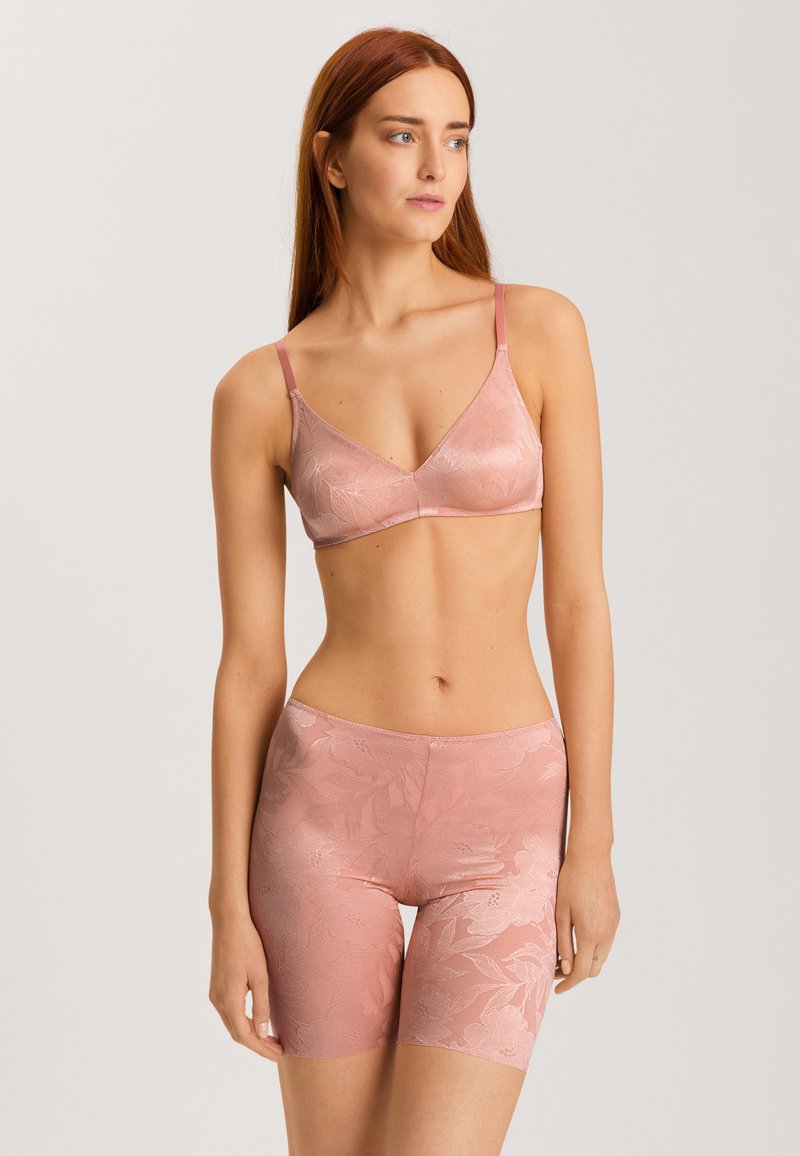 Vaaleanpunainen pitsinen bralette, jossa on säädettävät hihnat, sileä pinta ja kukkakuosi. Yhdistetty saman sävyisiin pitsisiin shortseihin.
