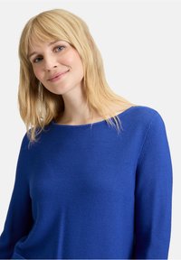 Blauer Strickpullover mit weitem Bootsausschnitt und langen Ärmeln. Der Stoff hat ein strukturiertes Muster und eine lockere Passform.