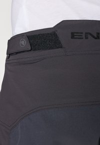 Pantalones cortos deportivos negros con una textura suave, que cuentan con una cinturilla ancha con Velcro y acentos cosidos para un ajuste seguro y durabilidad.