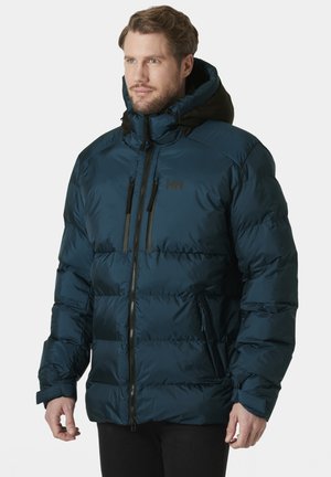 Chaqueta acolchada de color azul oscuro con un acabado brillante, capucha negra, cierre frontal con cremallera y dos bolsillos en el pecho con cremallera. Presenta puños elásticos y un diseño acolchado.