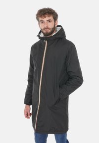 Giacca nera con cappuccio, zip frontale e accenti a strisce colorate. Presenta un design lungo e morbido con due tasche laterali. Realizzata in materiale testurizzato.