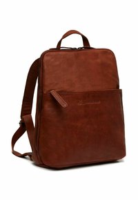 Mochila de cuero marrón con forma rectangular, un asa superior, correas ajustables y un bolsillo delantero con cremallera. Textura suave y mate.