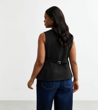Top sans manches noir avec un accent de style ceinture dans le dos, associé à un jean taille haute bleu foncé, présenté sur un fond uni.