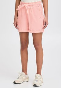 Lys rosa, teksturerte shorts med elastisk midje og frontknyting. Har oppbrettede mansjetter og sidelommer. Kombinert med beige sneakers.