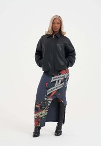 Černá kožená bomber bunda se zipem, doplněná modrou sukní s květinovým vzorem a textem, střiženou s bočním rozparkem.