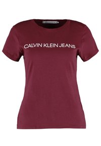 Camiseta de algodón burdeos con cuello redondo y mangas cortas. En el frontal se muestra el texto "CALVIN KLEIN JEANS" en blanco.