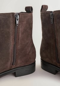 Botines de ante marrón con cremalleras laterales, un tacón bajo en bloque y detalle de costura en contraste en las costuras.
