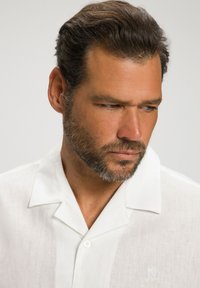 Chemise blanche en lin à manches courtes avec un col classique, dotée d'une patte de boutonnage et d'un détail de logo brodé sur la poitrine.