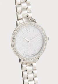 Silver metal watch with a glittery silver face, linked bracelet, and crystal accents around the bezel. Features simple hour markers and hands.