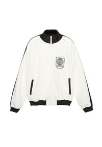 Hvid zip-up jakke med sort krave, manchetter og lommeindlæg; sorte striber ned ad ærmerne; globepatch med stjerner på brystet.