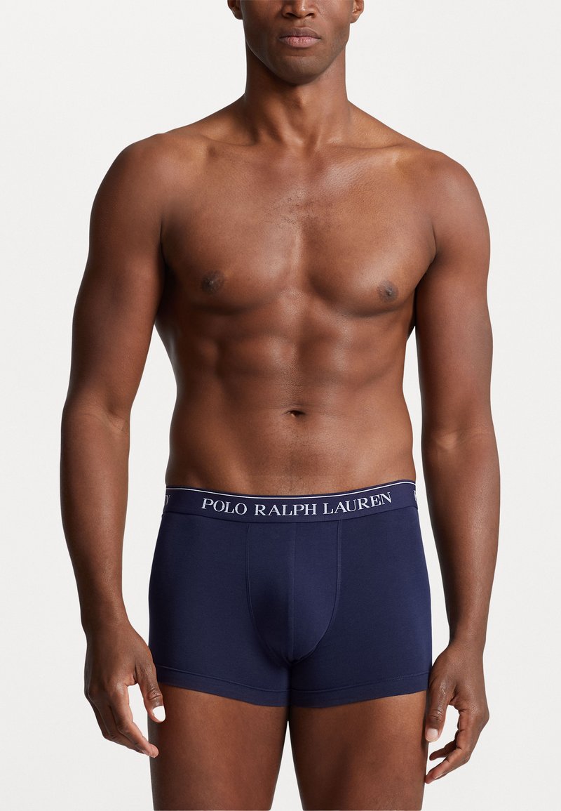 Caleçons boxers en coton stretch marine avec une ceinture à logo blanche, design ajusté et texture lisse. Aucun autre vêtement ou détail visible.