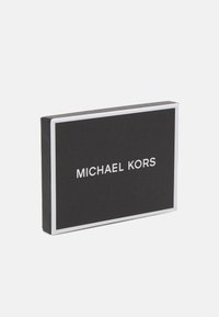 Boîte rectangulaire noire avec une surface texturée, bordure blanche et le nom de la marque "MICHAEL KORS" affiché en lettres blanches.