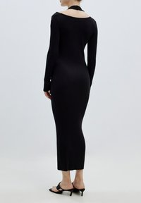 Schwarzes geripptes Kleid mit langen Ärmeln, schulterfreier Ausschnitt und Mid-Cap-Länge. Es hat ein figurbetontes Design und eine glatte Textur.