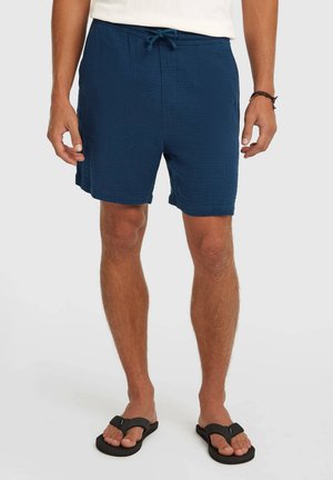 Tumesinised, tekstuuriga lühikesed püksid, millel on elastne vöökoht ja pael. Kantud mustade varbavaheplätudega, lihtsa disaini ja vaba lõikega.