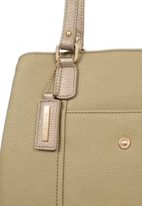 Groene leren handtas met een gestructureerde afwerking, voorzien van een gouden strap en hardware, met een label dat met een ketting is bevestigd.