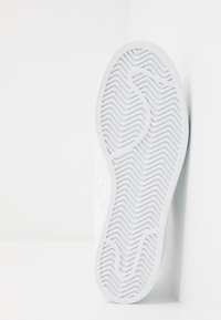 White sneaker sole featuring a zigzag tread pattern, smooth edges, and a slightly raised design. Material appears rubber with a textured finish.