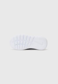 Balta guma sportinė batų padas su tekstūriniu raštu, kuriame ryškiai matomas Nike logotipas ir tinklelio formos protektorius, užtikrinantis sukibimą.