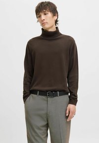 Brown turtleneck sweater in soft fabric, paired with grey trousers. The outfit features a black belt with a silver buckle.